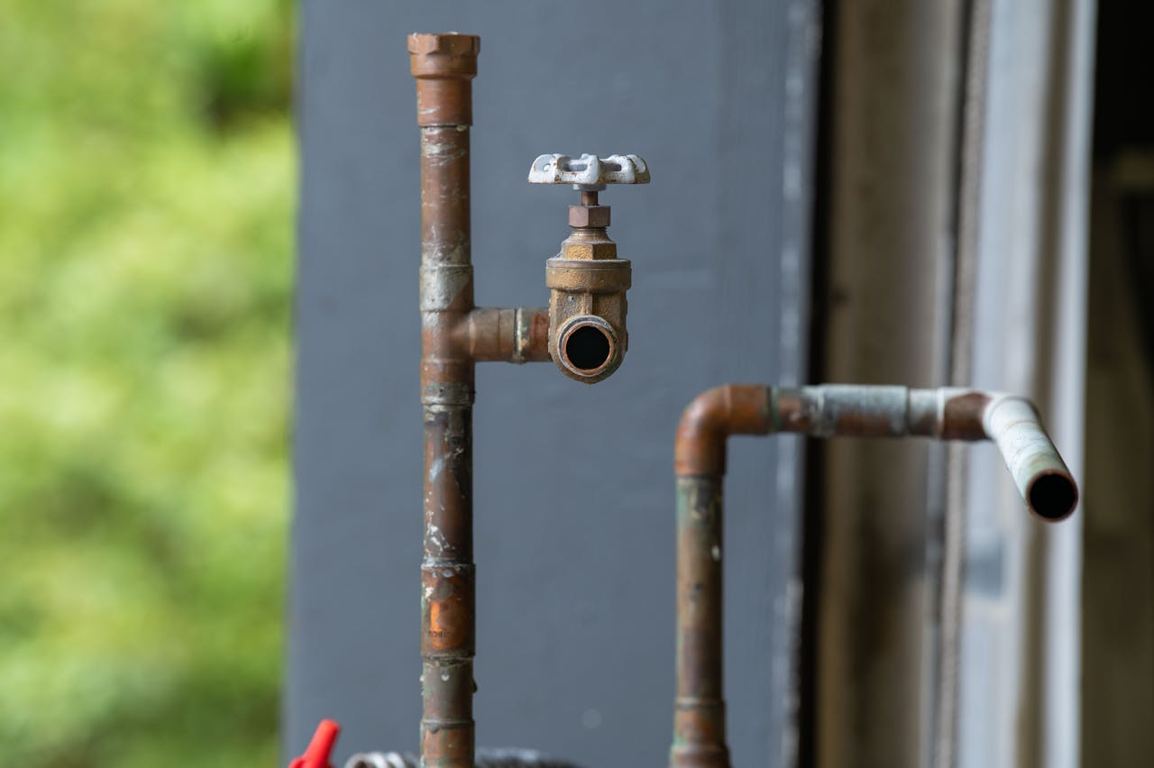 Detailed view of an old, rusty industrial water pipe with valve, conveying vintage industrial aesthetics.