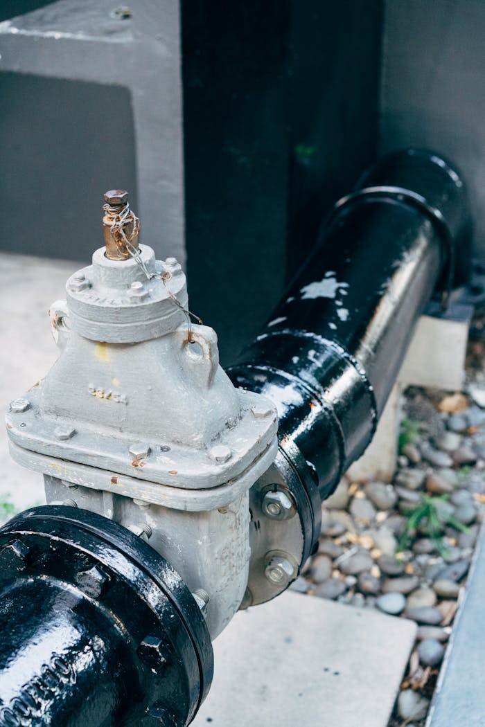 Detailed view of a plumbing valve with connected black pipeline, essential for industrial applications.
